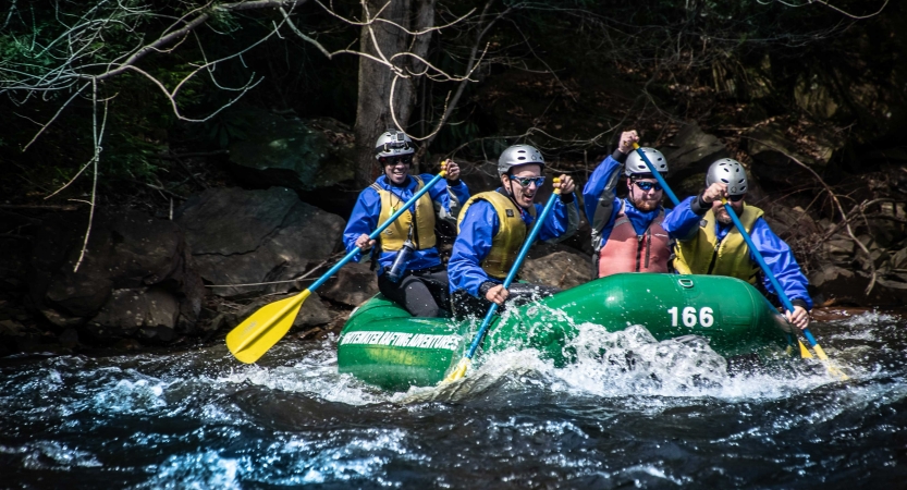 a group of veterans paddle a raft on an outward bound course